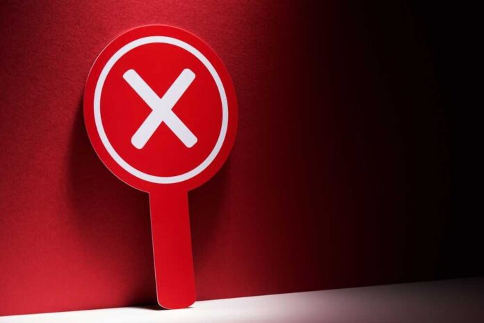 Red sign with a white 'X' symbol against a dark background