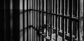 Rusty prison cell bars in dim lighting.