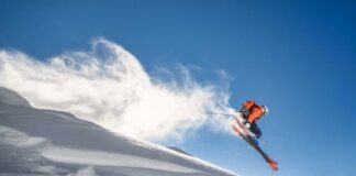 Skier jumping off a snow-covered slope against a clear blue sky