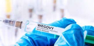Close-up of a syringe labeled Wegovy with a gloved hand holding it