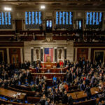 A crowded congressional chamber with members gathered around the central podium