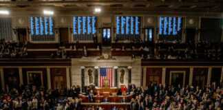 A crowded congressional chamber with members gathered around the central podium