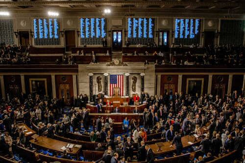 A crowded congressional chamber with members gathered around the central podium