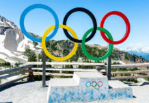 Olympic rings and podium with mountain backdrop.