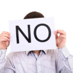 Person holding a sign that says 'NO' in large letters