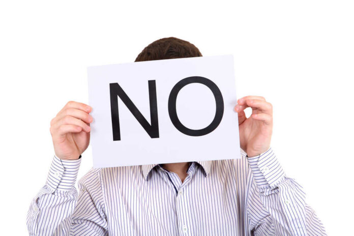 Person holding a sign that says 'NO' in large letters