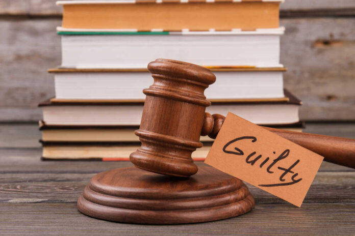 shutterstock_1906952809.jpg A wooden gavel with a tag reading 'Guilty' next to stacked books