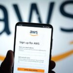 Mobile phone displaying AWS signup page with logo in background