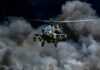 Military helicopter flying through a cloud of smoke