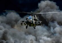 Military helicopter flying through a cloud of smoke