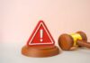 A red warning sign next to a legal gavel on a light background