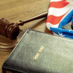 Gavel, Holy Bible, and American flag on a desk.