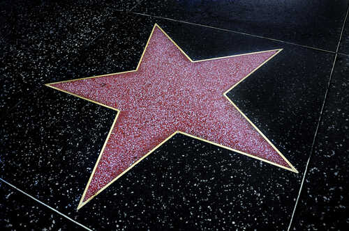A red star embedded in a black sidewalk, part of the Hollywood Walk of Fame