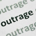 Close-up of the word 'outrage' printed in bold on paper