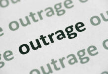 Close-up of the word 'outrage' printed in bold on paper