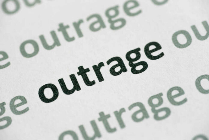 Close-up of the word 'outrage' printed in bold on paper