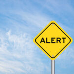 Yellow alert sign against a blue sky