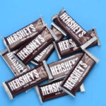 Hershey Bows to Pressure – Recipe Restoration PROMISED A pile of Hershey's milk chocolate bars on a blue background
