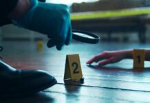 A detective examining evidence at a crime scene with markers on the floor