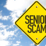 Yellow warning sign displaying 'SENIOR SCAM' against a blue sky