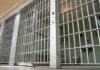 Empty prison cell with metal bars and toilet.