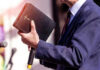 Apology SHOCKER: Vatican’s Slavery Role Exposed Man holding a Bible during a speech or presentation.