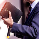 Apology SHOCKER: Vatican’s Slavery Role Exposed Man holding a Bible during a speech or presentation.