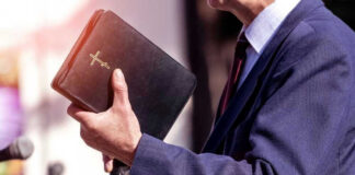 Man holding a Bible during a speech or presentation.