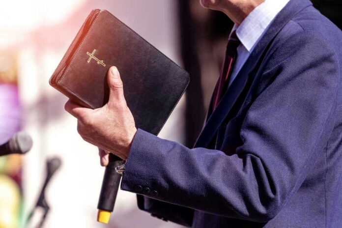 shutterstock_2074457752 Man holding a Bible during a speech or presentation.