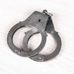 Secret Service Agent Arrested For Disgusting Act A pair of metallic handcuffs resting on a light wooden surface