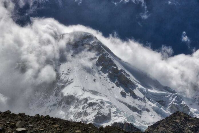 shutterstock_2651823425.jpg Snow-covered mountain peak partially obscured by clouds