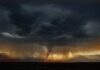 A dramatic storm with dark clouds and a lightning strike over mountains