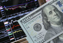 Economist Warns: Stock Market Disconnected From Reality A close-up of a hundred-dollar bill in front of stock market graphs