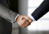 Two people in business suits shaking hands.