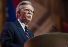 Bolton’s Shocking Flip: Guilty, But Why So Light? Man speaking at a podium with microphone.