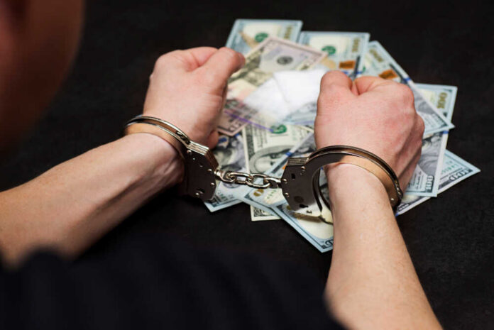 Person in handcuffs surrounded by cash