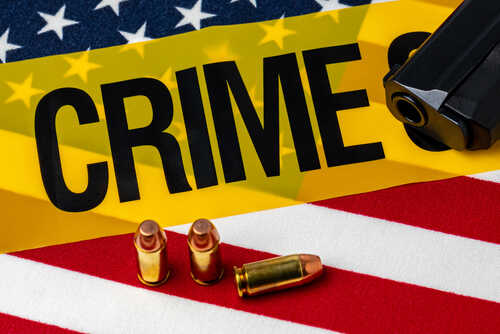 Gun,,Ammunition,,Crime,Scene,Tape,And,American,Flag.,Concept,Of A gun and bullets on an American flag with a crime scene marker