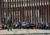 Border Bombshell: Trump Scores Supreme Win Border patrol officer watches group sitting by a fence.