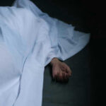 Chilling Kyoto Hike Ends In Death Hand emerging from under white sheet on dark surface.