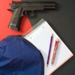 Handgun beside school supplies and a blue backpack