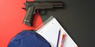 Handgun beside school supplies and a blue backpack