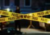 VIDEO: Wanted Gunman Terrorizes Town Police tape marking a crime scene with blurred figures in the background