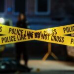 VIDEO: Wanted Gunman Terrorizes Town Police tape marking a crime scene with blurred figures in the background