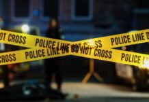 VIDEO: Wanted Gunman Terrorizes Town Police tape marking a crime scene with blurred figures in the background
