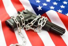 A handgun wrapped in chains on an American flag