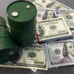 Oil Freefall After Trump Move Two green oil barrels placed on a pile of hundred dollar bills