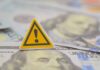 Debt Bubble Quietly Goes Critical A warning sign placed on top of U.S. dollar bills