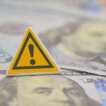 Debt Bubble Quietly Goes Critical A warning sign placed on top of U.S. dollar bills