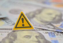Debt Bubble Quietly Goes Critical A warning sign placed on top of U.S. dollar bills