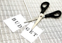 Scissors cutting a paper labeled 'BUDGET' on a financial spreadsheet